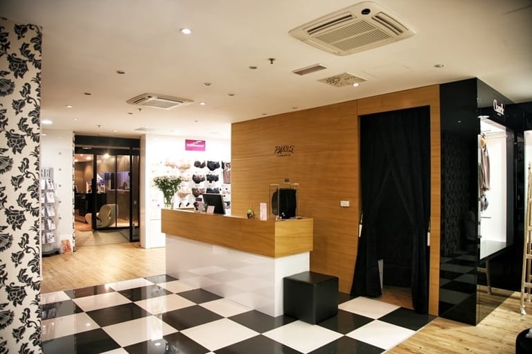 Modern salon reception area with wooden counter, checkered floor, black and white decor, and contemporary lighting