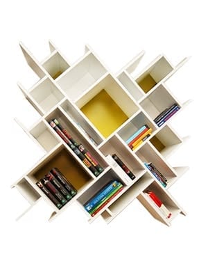 Geometric white wall-mounted shelving unit with books and decorative items arranged at various angles